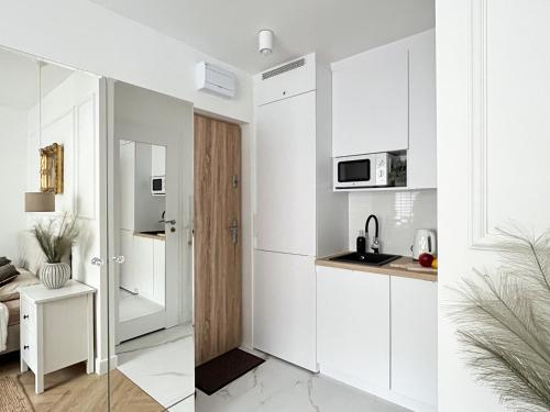 a white kitchen with white cabinets and a sink at Apartament zielony Mokotów in Warsaw