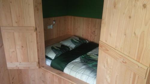 a small room with a bed in a wooden cabin at boerenskuur De Bedstee groen in Assendelft