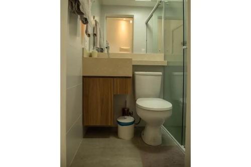 een badkamer met een toilet, een wastafel en een spiegel bij Para casais, prédio beira mar, em frente à Roda Gigante in Balneário Camboriú