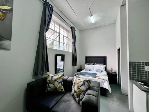 1 dormitorio con cama, sofá y ventana en Posh Apartment next to Maboneng, en Johannesburgo