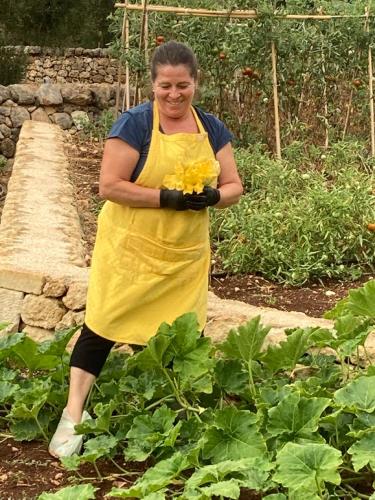 a woman standing in a garden holding flowers at Boutique Hotel Masseria Sottomasi in Savelletri di Fasano