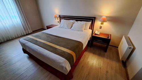 a hotel room with a large bed and a night stand at Hotel Diego de Almagro Puerto Montt in Puerto Montt