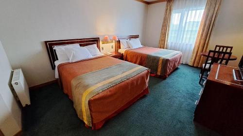 a hotel room with two beds and a window at Hotel Diego de Almagro Puerto Montt in Puerto Montt