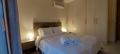 een slaapkamer met een wit bed en 2 handdoeken bij Krystal Apartment in Athene