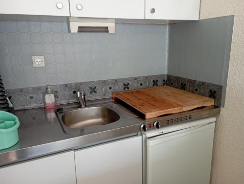 a kitchen with a sink and a wooden cutting board at Appt 4 pers au Pla d' Adet, Résidence le Grand Stemm , station de ski Saint Lary in Saint-Lary-Soulan