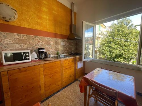 cocina con microondas, mesa y ventana en Levante Blu, en La Spezia