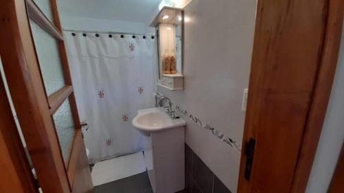Baño blanco con lavabo y espejo en La casa de Delia en Esquel