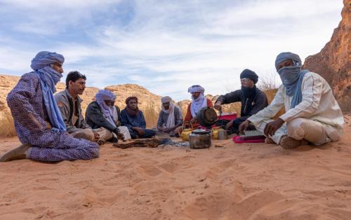 a group of people sitting in the sand at Mhamid Sahara Camp - Mhamid El Ghizlane in Mhamid