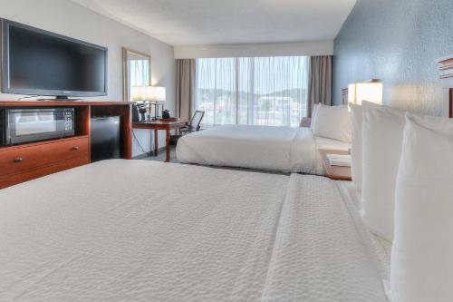 a hotel room with two beds and a flat screen tv at The Ramsey Hotel and Convention Center in Pigeon Forge