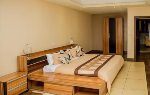 a bedroom with a large bed with a wooden headboard at Rohi Apartments in Kigali