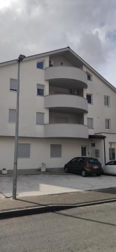 Un edificio con un coche aparcado en un estacionamiento. en Apartman Polaris Posušje, en Posušje