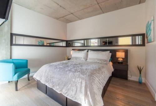 1 dormitorio con 1 cama grande y 1 silla azul en Les Immeubles Charlevoix - 760-416 en Quebec