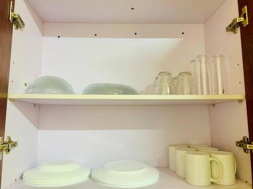 a cabinet with plates and glasses on a shelf at Casa Perlita, acogedora y privada. in Palenque