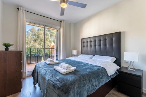 een slaapkamer met een groot bed en handdoeken bij Seaside Bliss 2BR Apartment with Tranquil Terrace Pool and Parking in Fuengirola
