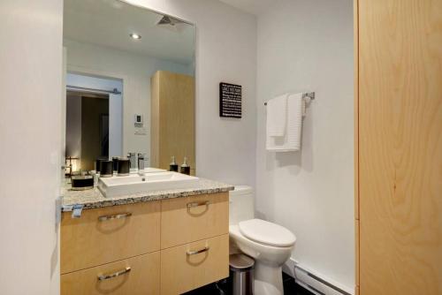 ein Badezimmer mit einem Waschbecken, einem WC und einem Spiegel in der Unterkunft Les Immeubles Charlevoix - 760-409 in Québec