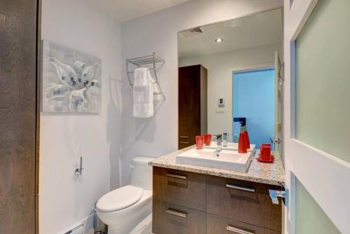 a bathroom with a sink and a toilet and a mirror at Les Immeubles Charlevoix - 760-510 in Quebec City