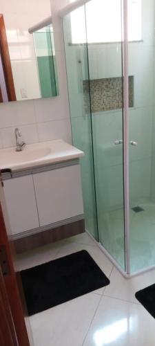 ein Bad mit einer Glasdusche und einem Waschbecken in der Unterkunft Ap dos sonhos 2 in Poços de Caldas
