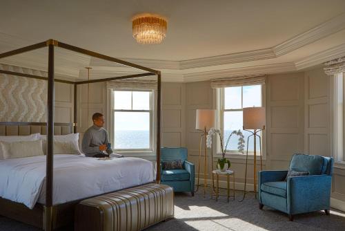 um homem num quarto com uma cama e duas cadeiras em The Ritz-Carlton, Half Moon Bay em Half Moon Bay