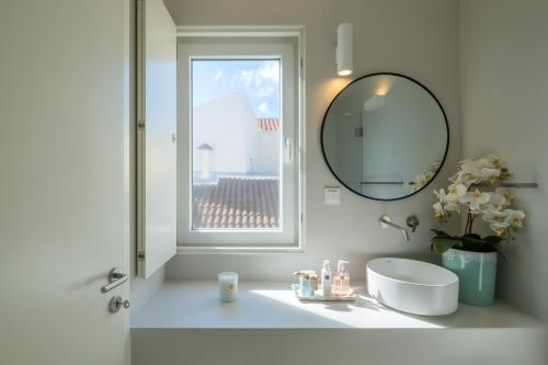 bagno bianco con lavandino e specchio di Casa dos Pedros (Beach House) a São Roque