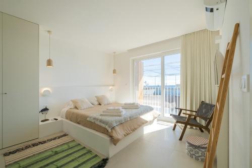 ein weißes Schlafzimmer mit einem Bett und einem Balkon in der Unterkunft Casa dos Pedros (Beach House) in São Roque