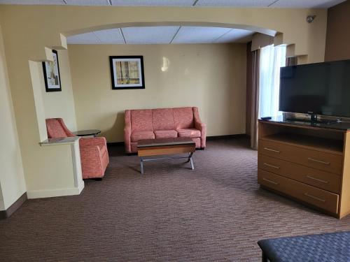 a living room with a couch and a flat screen tv at Wingate by Wyndham Greensboro-Coliseum in Greensboro