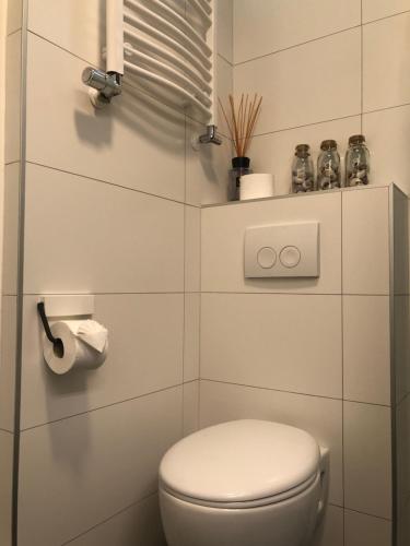 een witte badkamer met een toilet en een rol toiletpapier bij Zee & Zand in Noordwijk