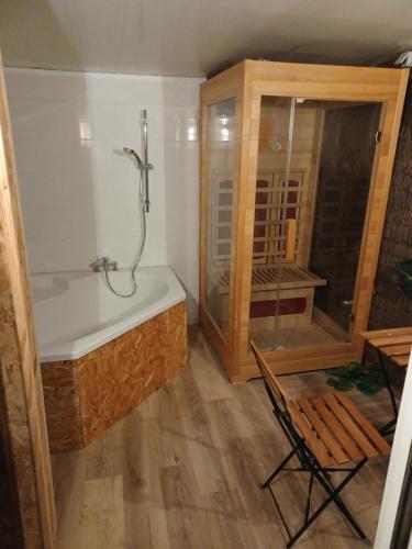 ein Badezimmer mit einer Badewanne und einem Stuhl darin in der Unterkunft Roulotte et sauna de Tonton Bouvy au domaine du Reuze in Winnezeele