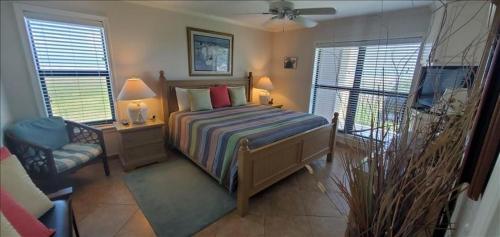 a bedroom with a bed and a chair and windows at Saida I Condos S1206 in South Padre Island