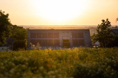 a building in a field with the sunset in the background at The Roost - a bird's eye view in the countryside in Cullompton