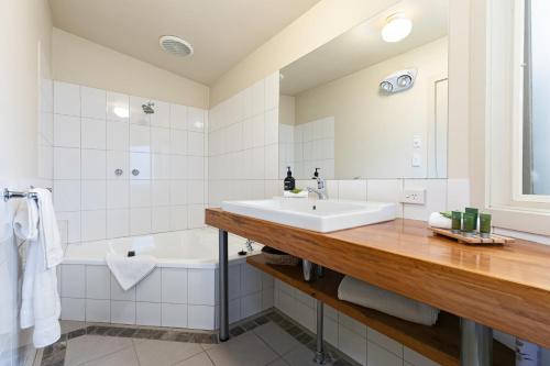 a bathroom with a sink and a tub and a mirror at Two Truffles Cottage Accommodation in Yarra Glen