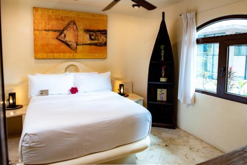 a bedroom with a white bed and a window at Villas Sacbe Condo Hotel and Beach Club in Playa del Carmen