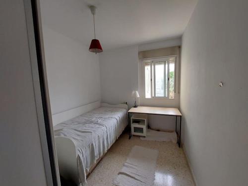 Habitación pequeña con cama y escritorio. en Piso céntrico de dos dormitorios, en La Línea de la Concepción