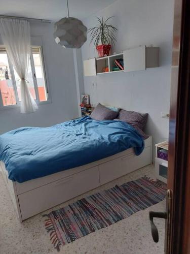 1 dormitorio con cama con sábanas azules y alfombra en Piso céntrico de dos dormitorios, en La Línea de la Concepción