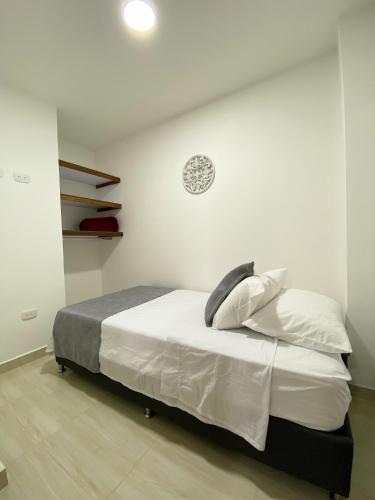 a bedroom with a bed with white sheets and a clock on the wall at Jardín de Primavera Apartamentos in Jardin