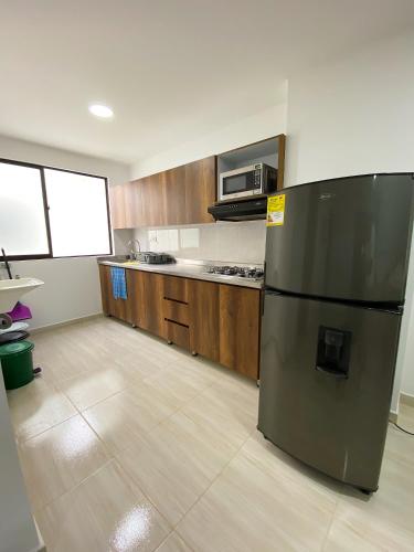 a kitchen with a black refrigerator and wooden cabinets at Jardín de Primavera Apartamentos in Jardin