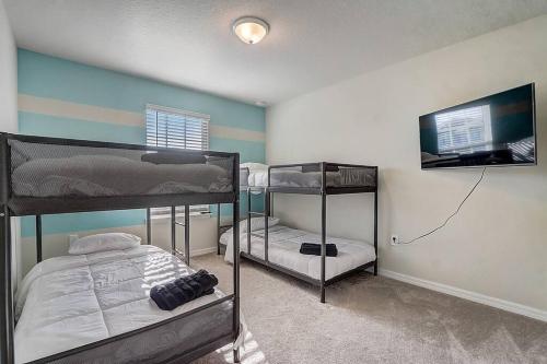 um quarto com 2 beliches e uma televisão de ecrã plano em luxury new 5 bedroom solterra resort close to disney em Davenport