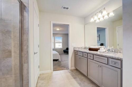 uma casa de banho com um chuveiro, um lavatório e um espelho. em luxury new 5 bedroom solterra resort close to disney em Davenport