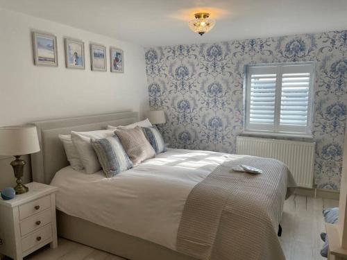 a bed in a bedroom with blue and white wallpaper at Once upon a tide in Kent