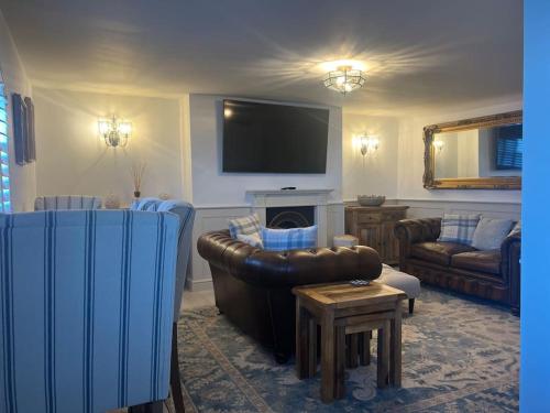 a living room with a leather couch and a tv at Once upon a tide in Kent