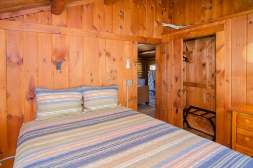 1 dormitorio con 1 cama en una pared de madera en Mountain Lake Cottages en Westmore