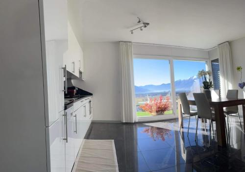 eine Küche und ein Esszimmer mit einem Tisch und einem großen Fenster in der Unterkunft Moderno bilocale vista lago Maggiore in Gordola