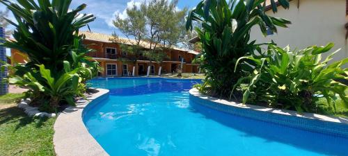 a swimming pool with two palm trees next to a building at COARE0100 - Condominio Aldeia Saint Sebastien in Arembepe