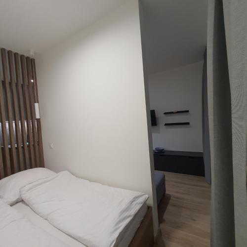 a small bedroom with a white bed and a room with at Apartament Holiday B 210 in Pobierowo