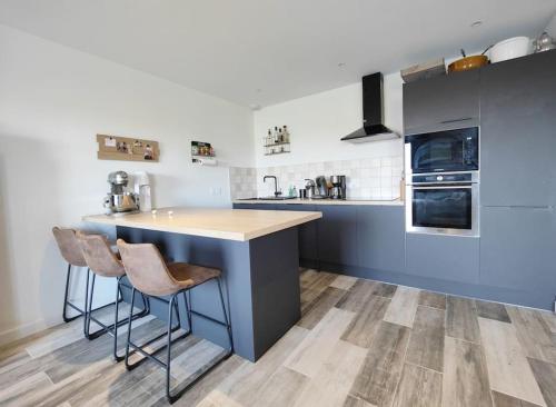 eine Küche mit einer Theke und 2 Hockern in der Unterkunft maison nature spéciale JO 2024 in Savignies