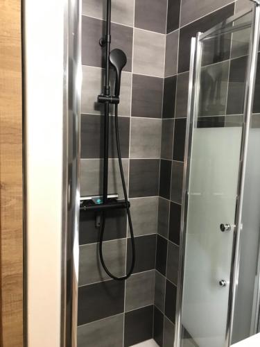 een douche met een zwarte en grijze tegelmuur bij L'HORIZON in Le Portel