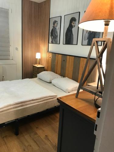 een slaapkamer met een bed met een lamp en foto's aan de muur bij L'HORIZON in Le Portel