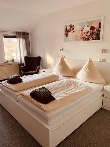 a large white bed in a room with a chair at Zum Deutschen Heinrich in Gifhorn