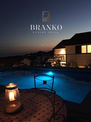 eine nächtliche Aussicht auf einen Pool mit einem Tisch und einer Kerze in der Unterkunft Villa Branko in Ravno