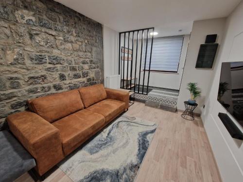a brown couch in a living room with a stone wall at Gîte Genius Loci in Marche-en-Famenne