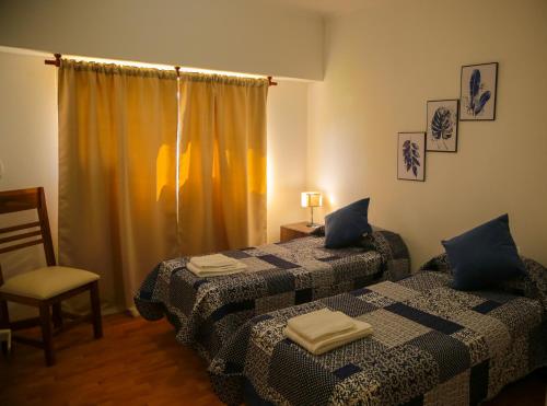 1 dormitorio con 2 camas, silla y ventana en Quinta La Inocencia en Trenque Lauquen